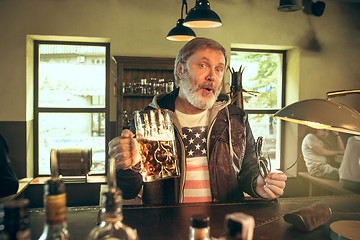 Image showing The senior bearded male drinking beer in pub