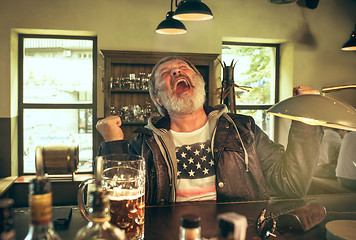 Image showing The senior bearded male drinking beer in pub