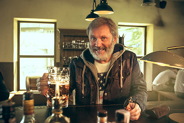 Image showing The senior bearded male drinking beer in pub