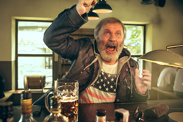 Image showing The senior bearded male drinking beer in pub