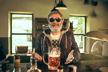 Image showing The senior bearded male drinking beer in pub