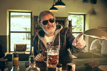 Image showing The senior bearded male drinking beer in pub