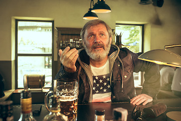 Image showing The senior bearded male drinking beer in pub