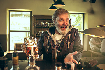 Image showing The senior bearded male drinking beer in pub