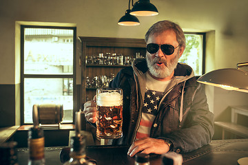 Image showing The senior bearded male drinking beer in pub