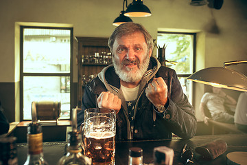 Image showing The senior bearded male drinking beer in pub