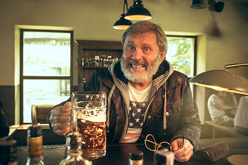 Image showing The senior bearded male drinking beer in pub