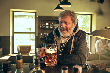 Image showing The senior bearded male drinking beer in pub