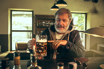 Image showing The senior bearded male drinking beer in pub