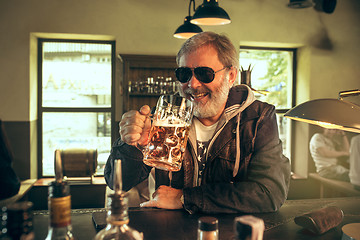 Image showing The senior bearded male drinking beer in pub