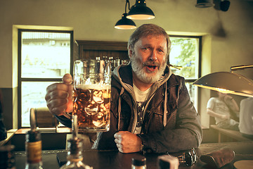 Image showing The senior bearded male drinking beer in pub