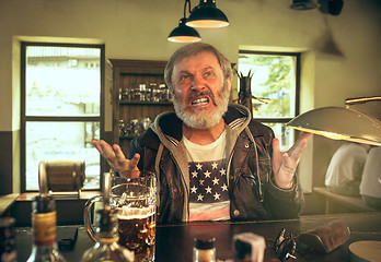 Image showing The senior bearded male drinking beer in pub