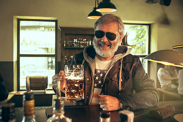 Image showing The senior bearded male drinking beer in pub