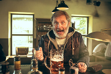 Image showing The senior bearded male drinking beer in pub