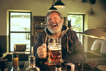 Image showing The senior bearded male drinking beer in pub