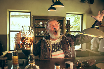 Image showing The senior bearded male drinking beer in pub