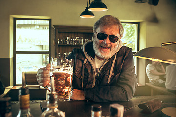 Image showing The senior bearded male drinking beer in pub