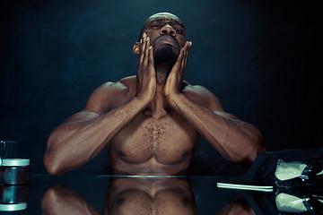 Image showing young man in bedroom sitting in front of the mirror after scratching his beard