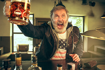 Image showing The senior bearded male drinking beer in pub