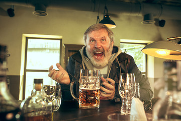 Image showing The senior bearded male drinking beer in pub