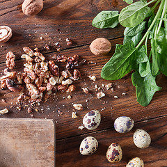 Image showing Fresh spinach, quail eggs, pieces of nuts on a wooden table with copy space. Healthy Salad Ingredients. Flat lay