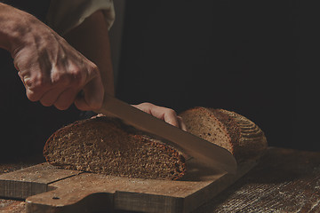 Image showing Hands cutting rye bread