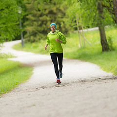 Image showing Sporty young female runner in city park..