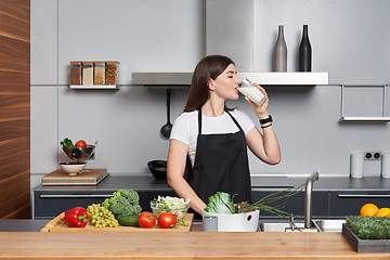 Image showing woman in the kitchen drinking milk