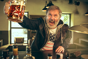 Image showing The senior bearded male drinking beer in pub