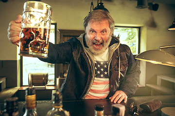 Image showing The senior bearded male drinking beer in pub