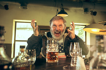 Image showing The senior bearded male drinking beer in pub