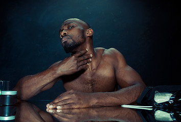 Image showing young man in bedroom sitting in front of the mirror after scratching his beard