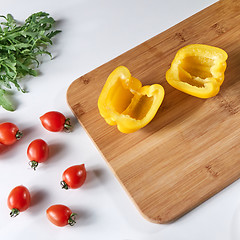 Image showing Fresh pepper halves, cherry tomatoes and arugula on a gray background with copy space. Ingredients for salad. Flat lay