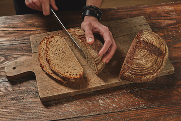 Image showing Hands cutting rye bread