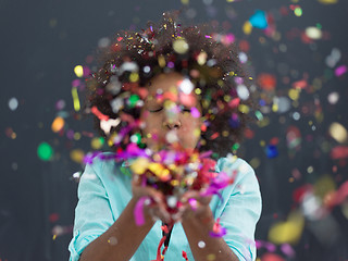 Image showing black woman blowing confetti in the air