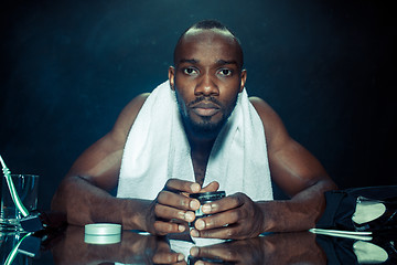 Image showing young man in bedroom sitting in front of the mirror after scratching his beard