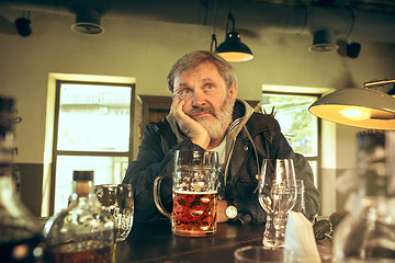 Image showing The sad senior bearded male drinking beer in pub