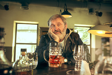 Image showing The sad senior bearded male drinking beer in pub