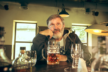 Image showing The sad senior bearded male drinking beer in pub