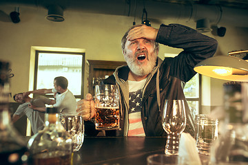 Image showing The senior bearded male drinking beer in pub