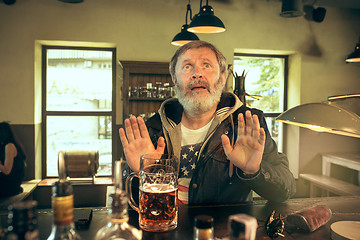 Image showing The senior bearded male drinking beer in pub