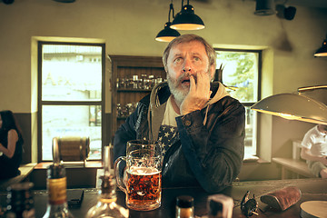 Image showing The sad senior bearded male drinking beer in pub