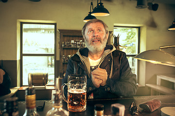 Image showing The senior bearded male drinking beer in pub