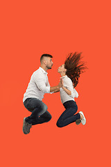 Image showing Freedom in moving. Pretty young couple jumping against red background