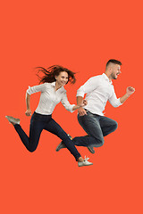 Image showing Freedom in moving. Pretty young couple jumping against red background