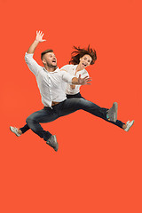 Image showing Freedom in moving. Pretty young couple jumping against red background