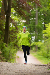 Image showing Sporty young female runner in the forest.