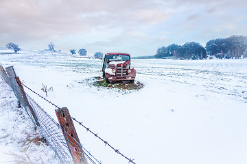 Image showing Rusty old car sits in a snow covered rural field