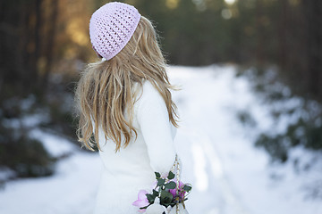 Image showing Woman standing on a snow covered road in forest