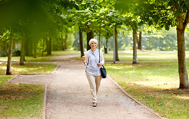 Image showing senior woman walking with takeaway coffee at park